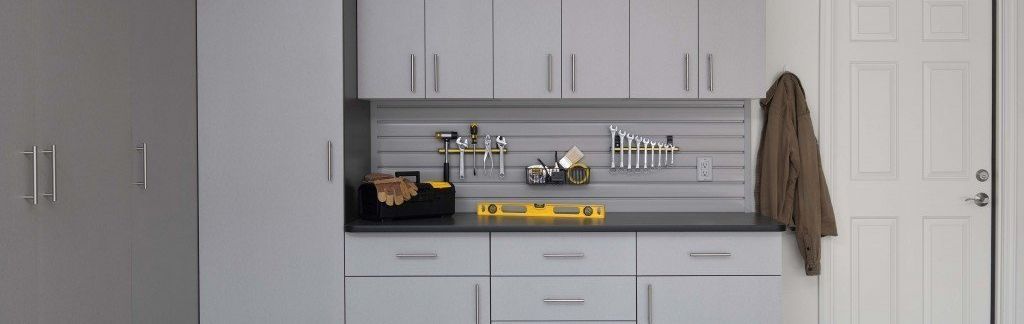 Garage storage cabinets and tools. A coat hangs on a white door.
