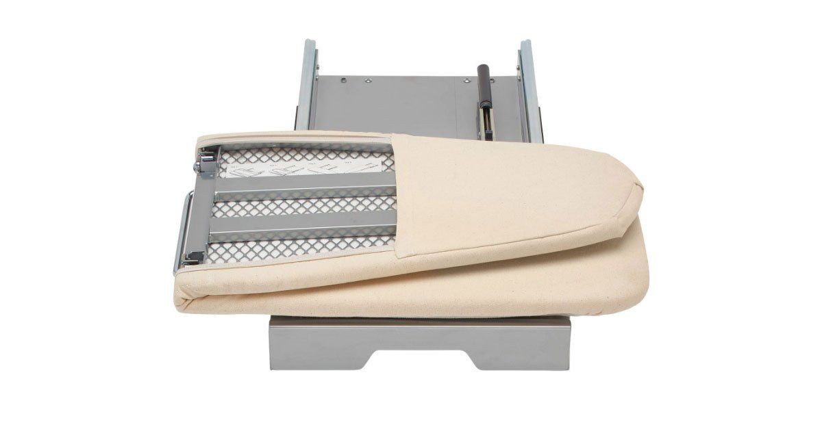 A white ironing board is sitting on top of a white table.