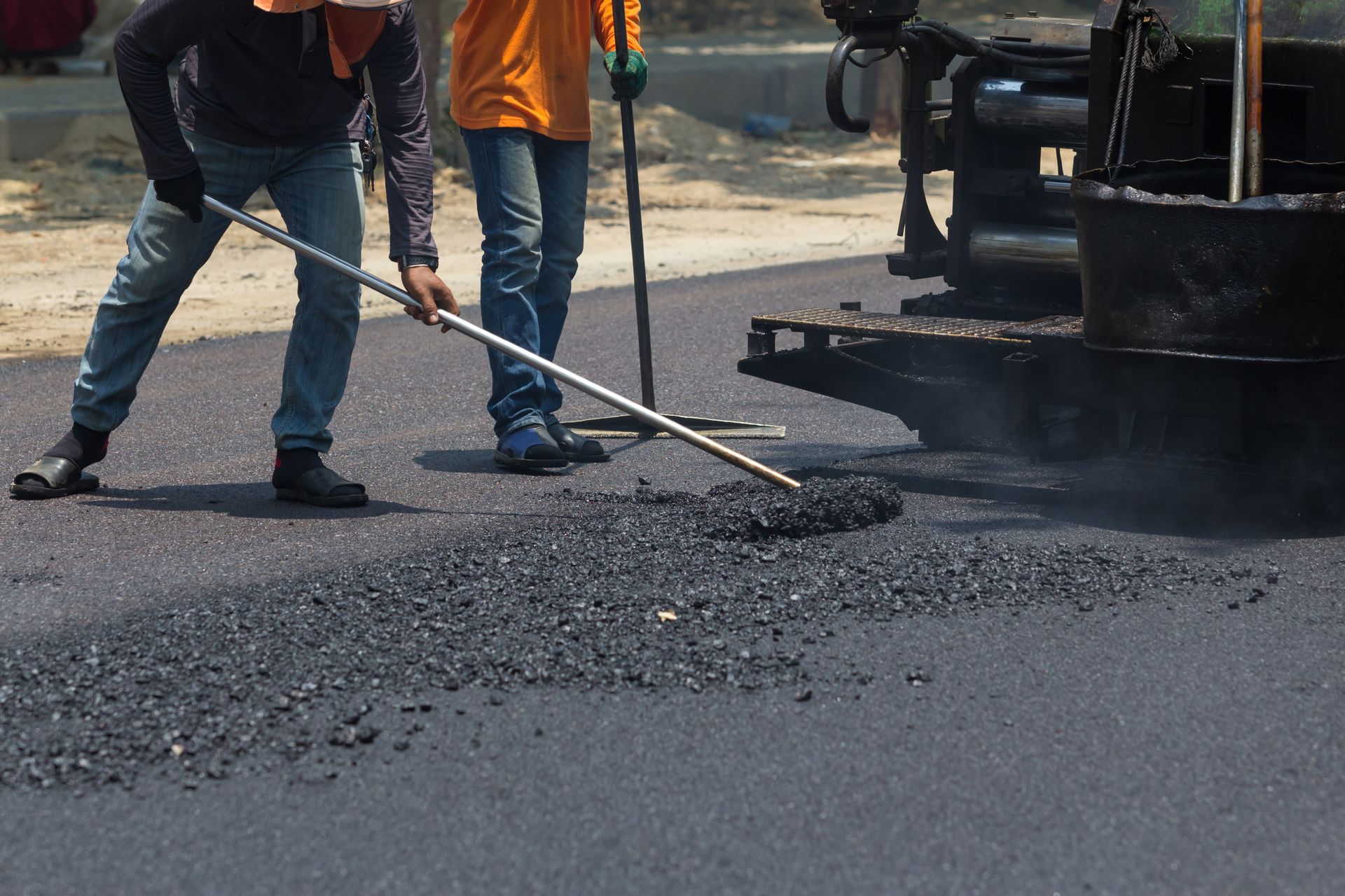 Deux hommes travaillent sur une route avec un balai.