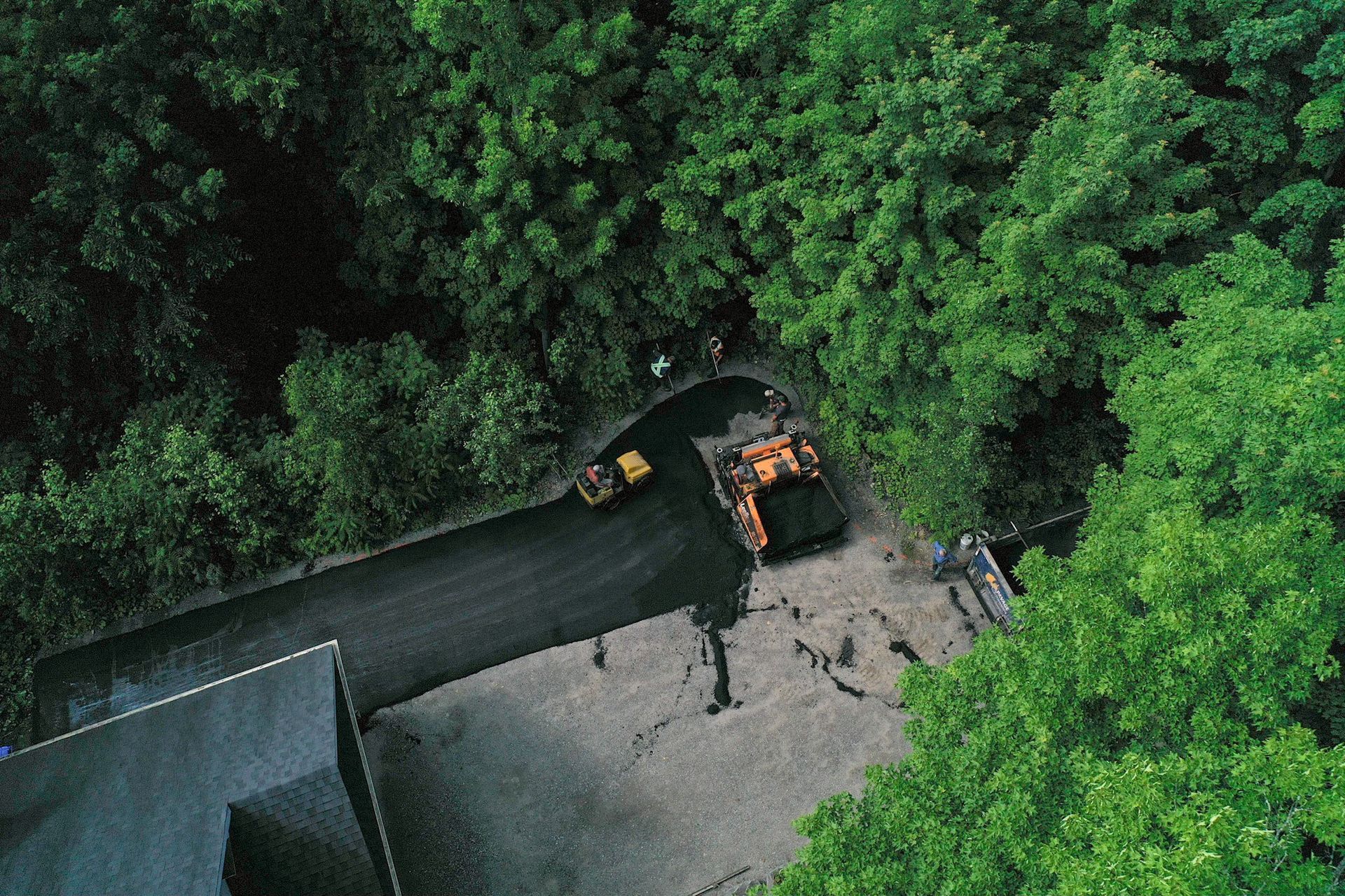Une vue aérienne d'un camion roulant sur une route entourée d'arbres.