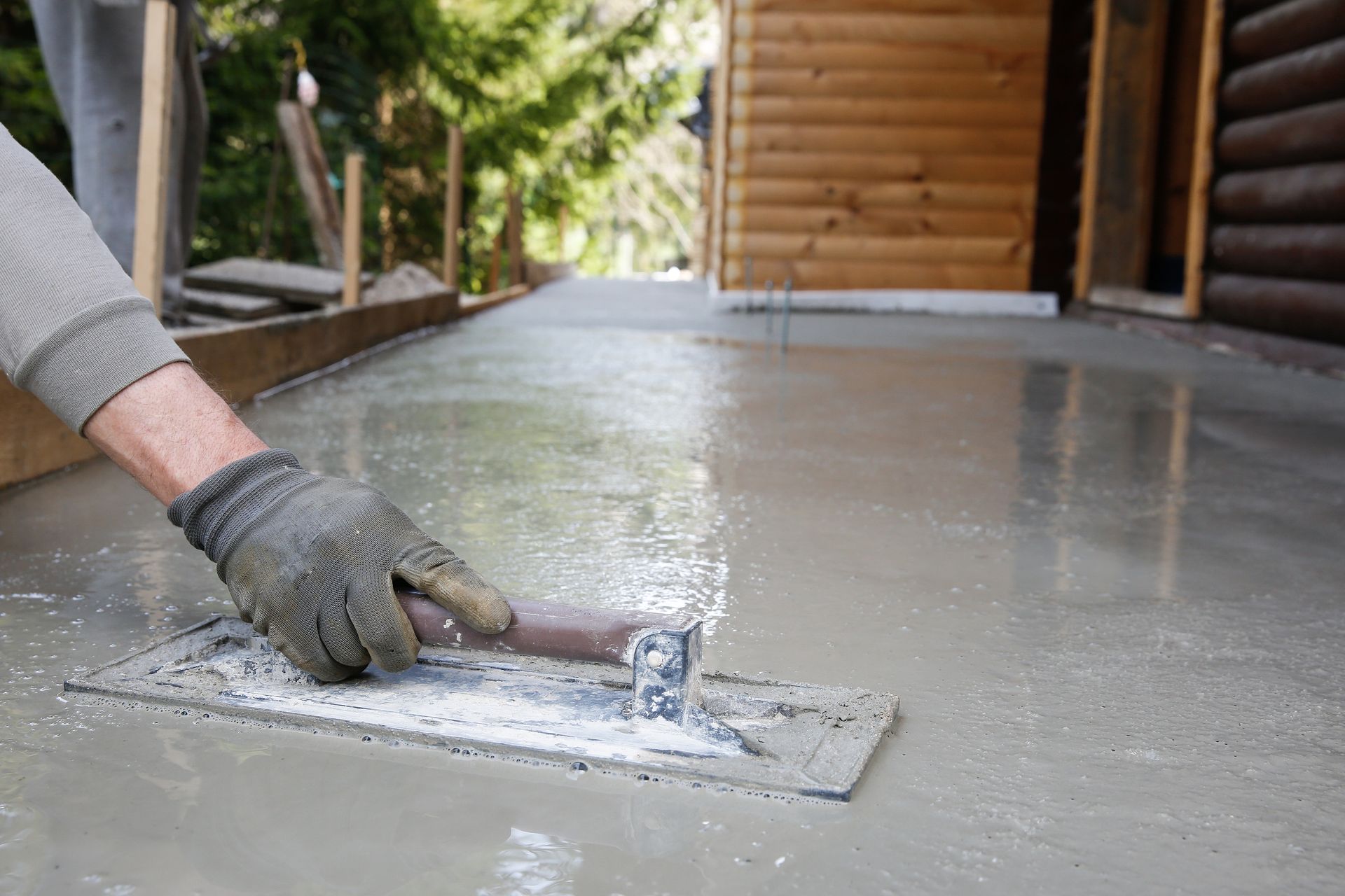 A mason leveling and screeding a concrete floor base.