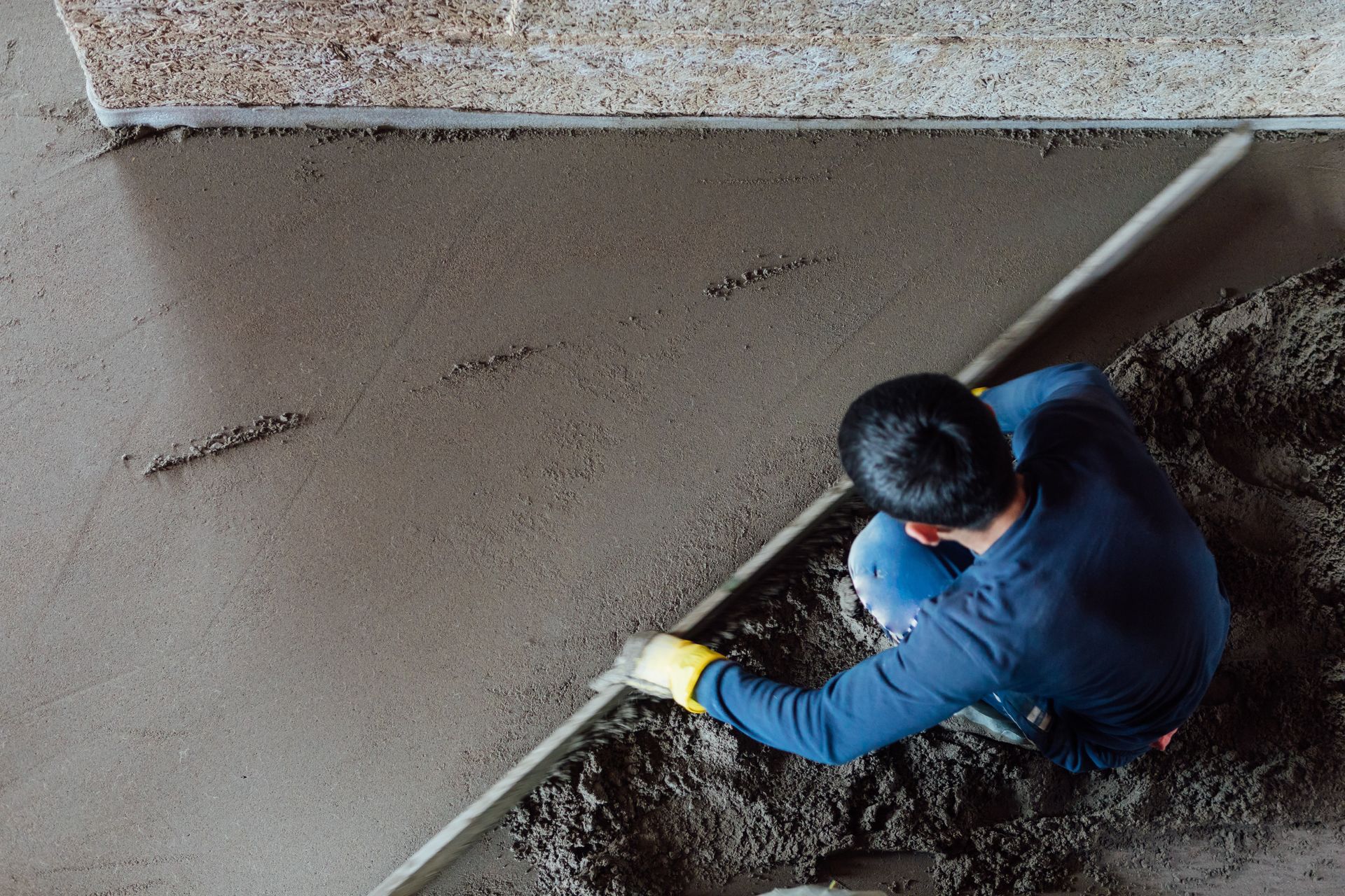 The top view of a mason smoothing a concrete floor.