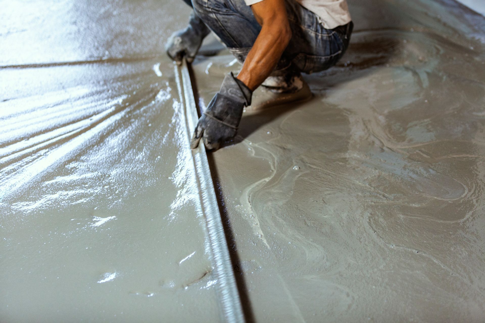 Close-up image of a construction contractor smoothing the wet concrete floor.
