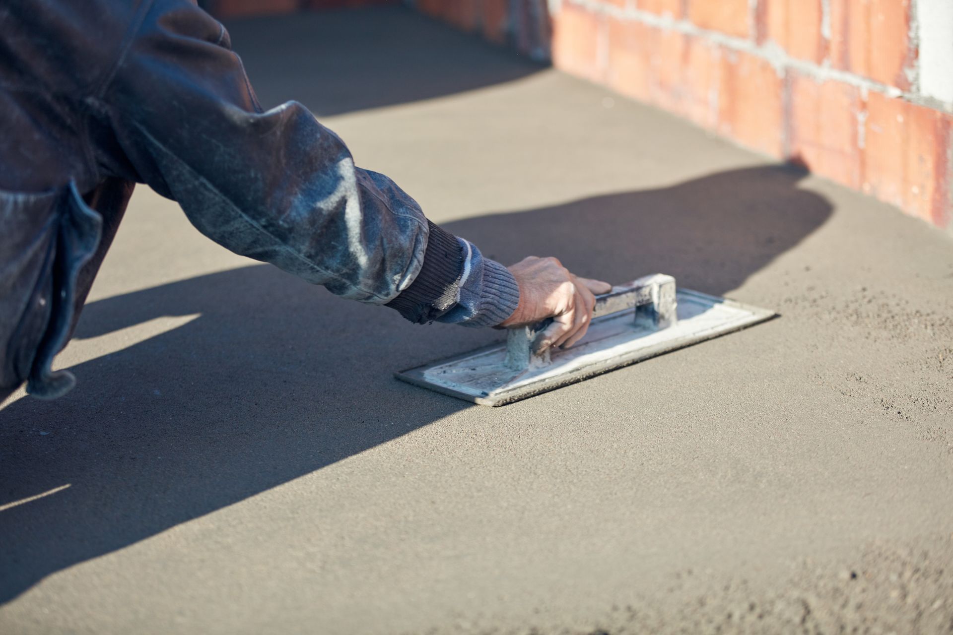 Close-up of a construction worker leveling concrete pavement.