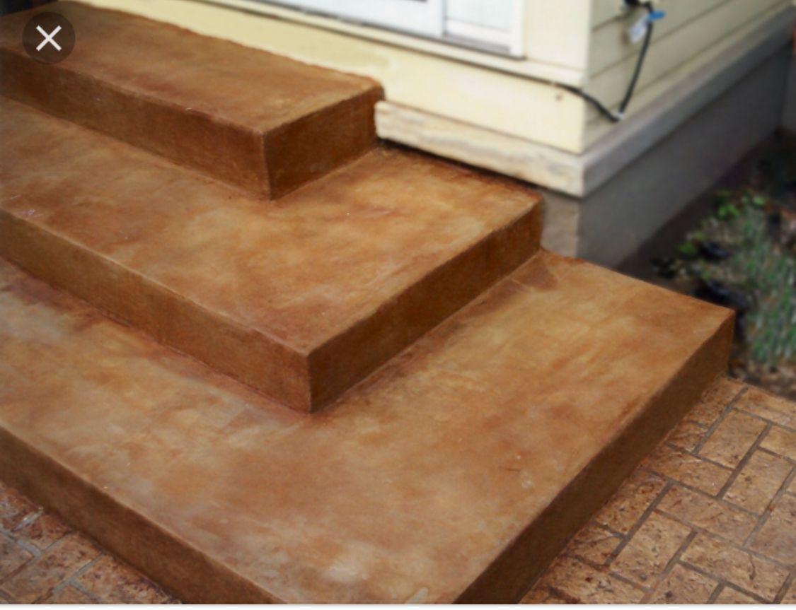 Brown stained concrete steps leading to a building with a light beige siding.