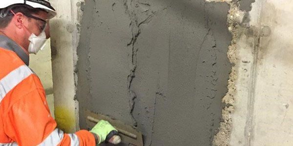Technician troweling cement patch to repair a spalled concrete wall in Bushnell