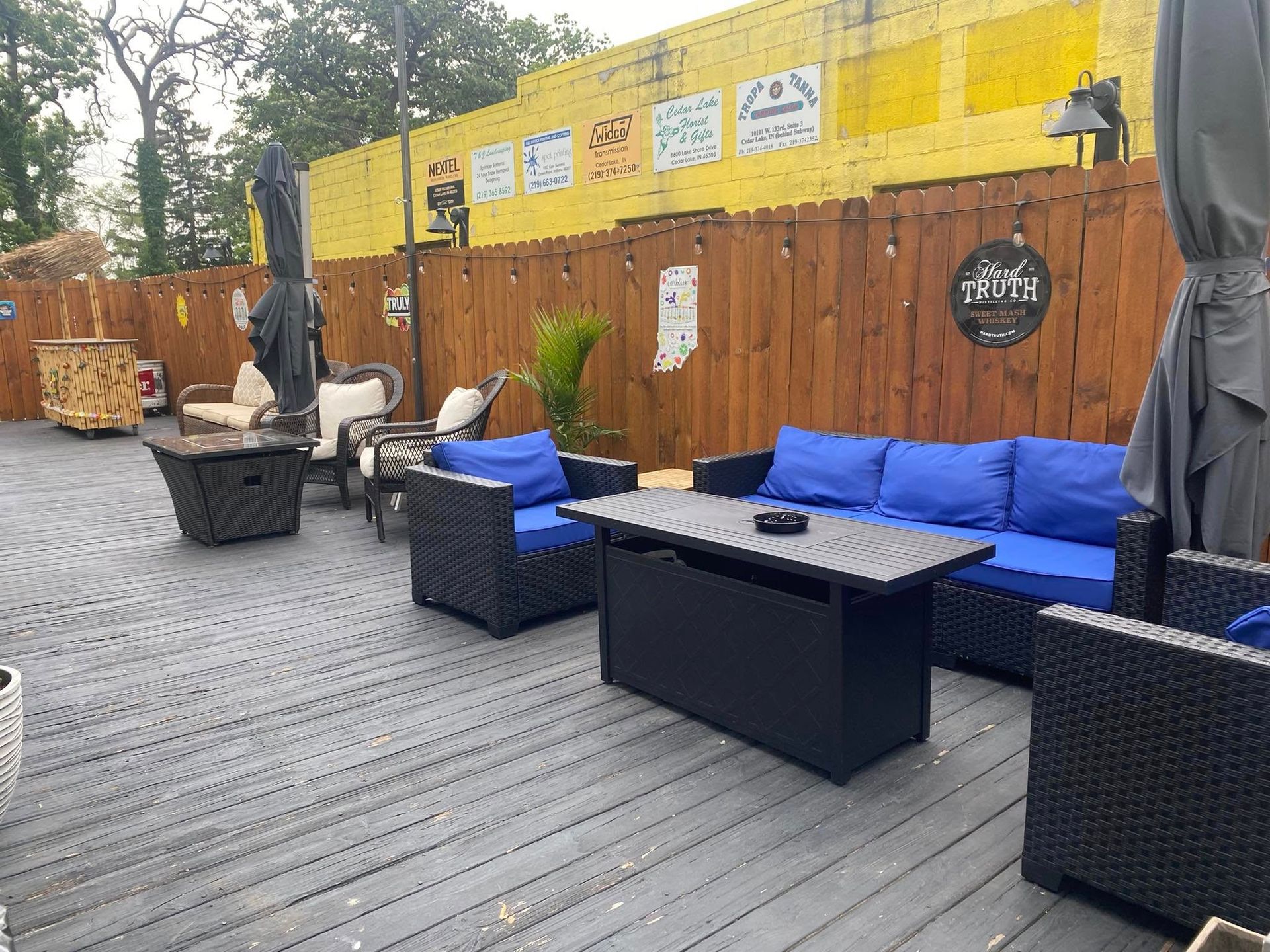 Outdoor patio with blue cushioned furniture, wooden deck, and yellow wall.