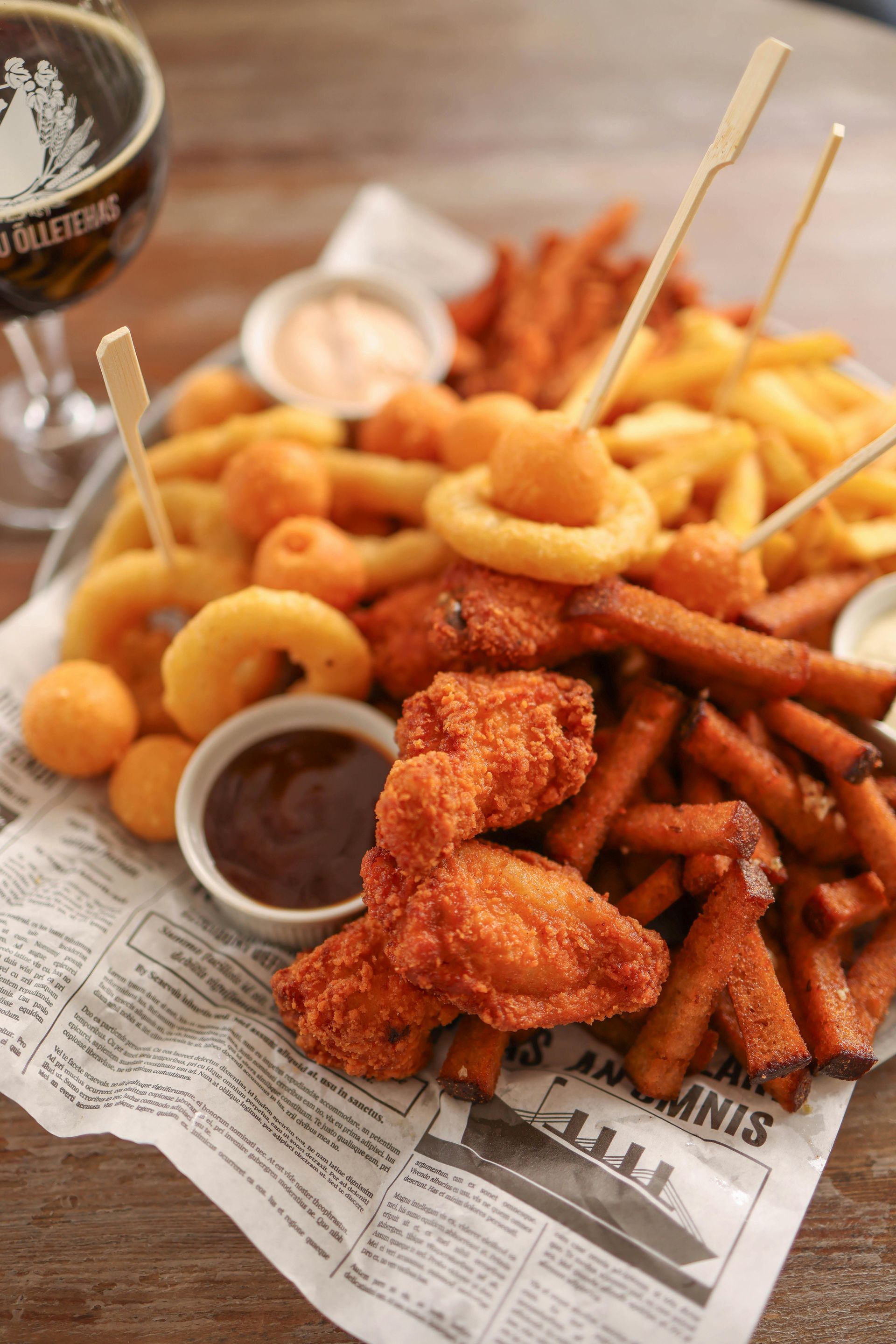 A platter of fried food, including wings, onion rings, fries, and dipping sauces.