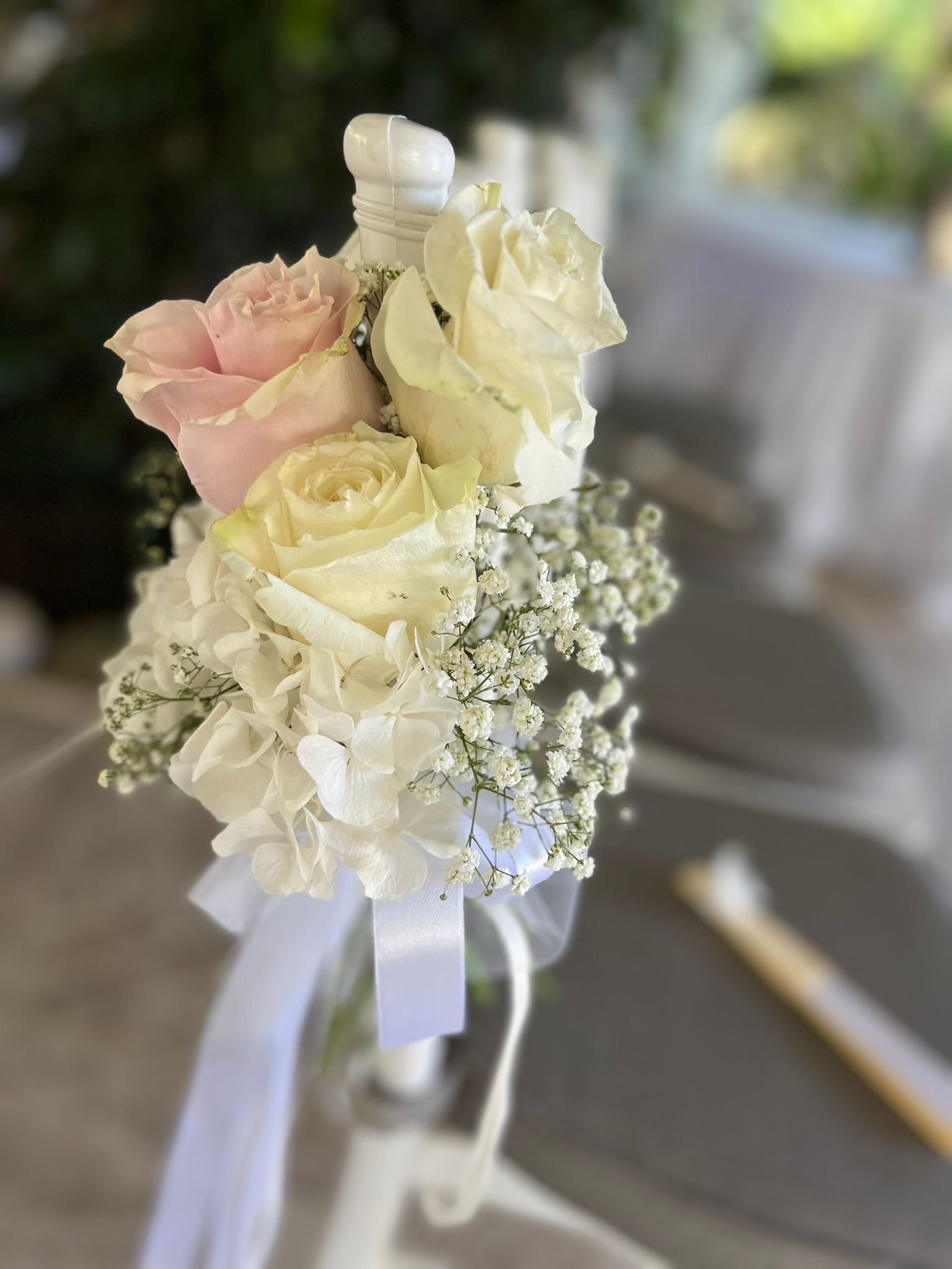 Bouquet di rose rosa e bianche, gypsophila e nastro su una tavola apparecchiata.