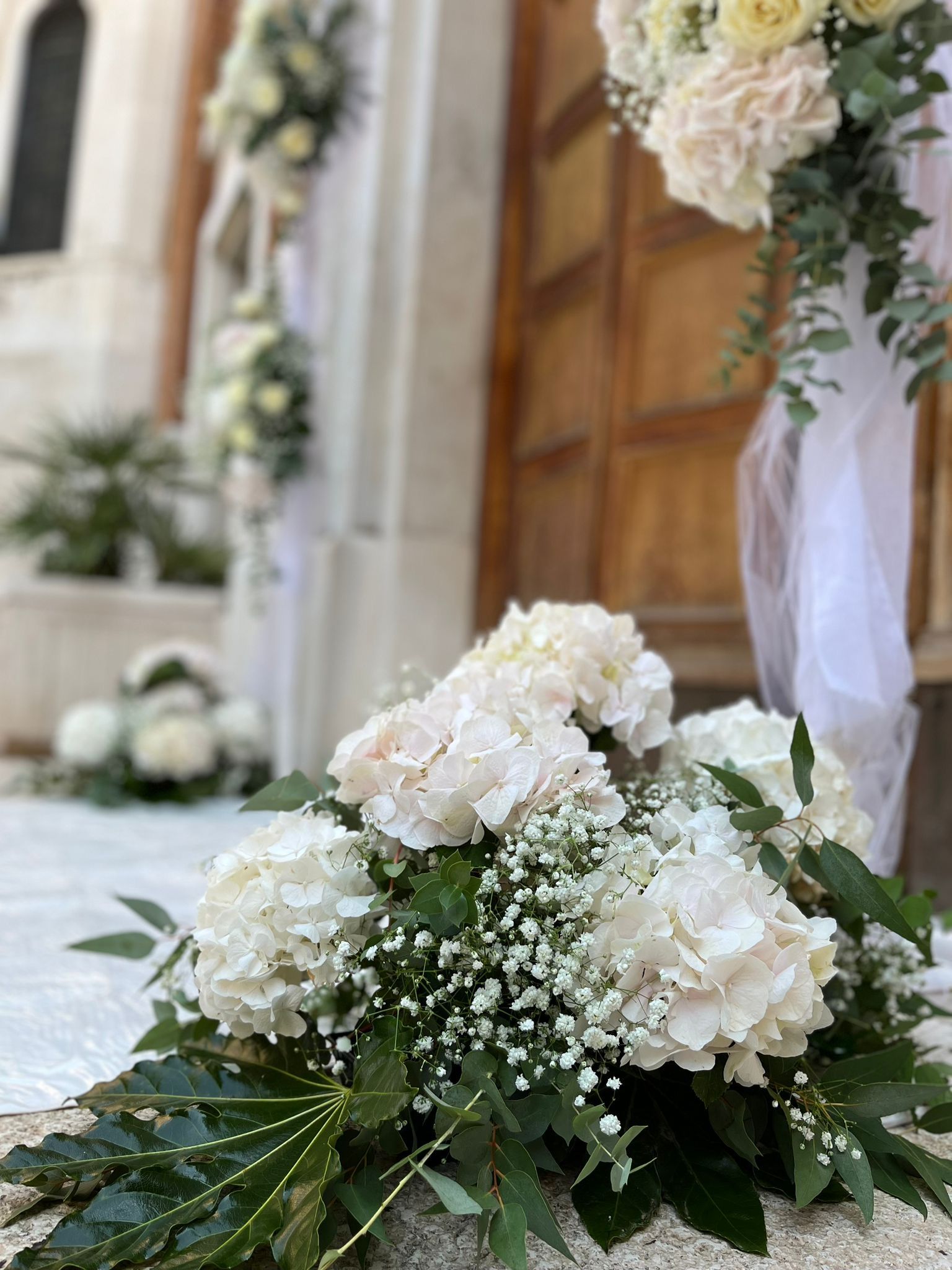 Mano che regge un piccolo bouquet di fiori bianchi su un vestito bianco.