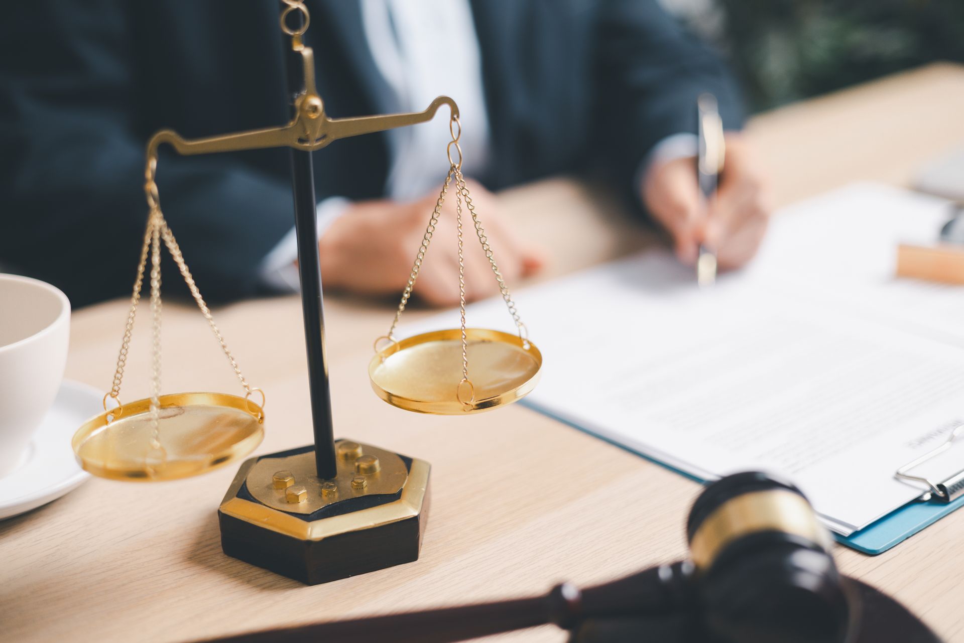 Lawyer’s desk with brass scales of justice beside paperwork and a gavel