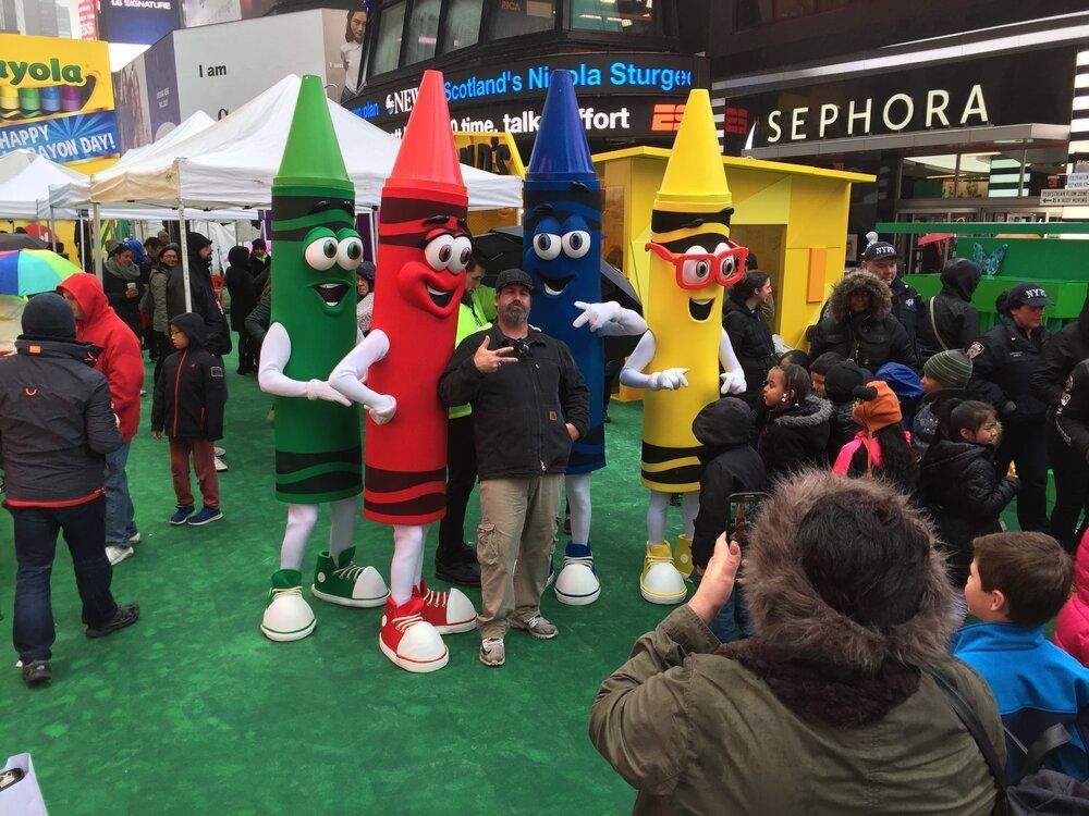 A woman is taking a picture of a group of crayon mascots