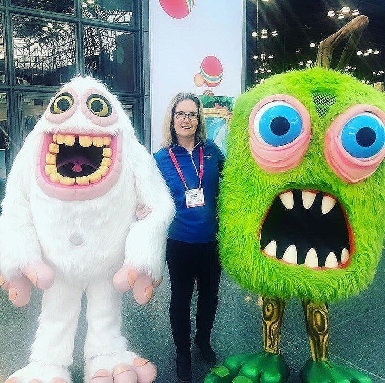 A woman is standing next to two stuffed monsters