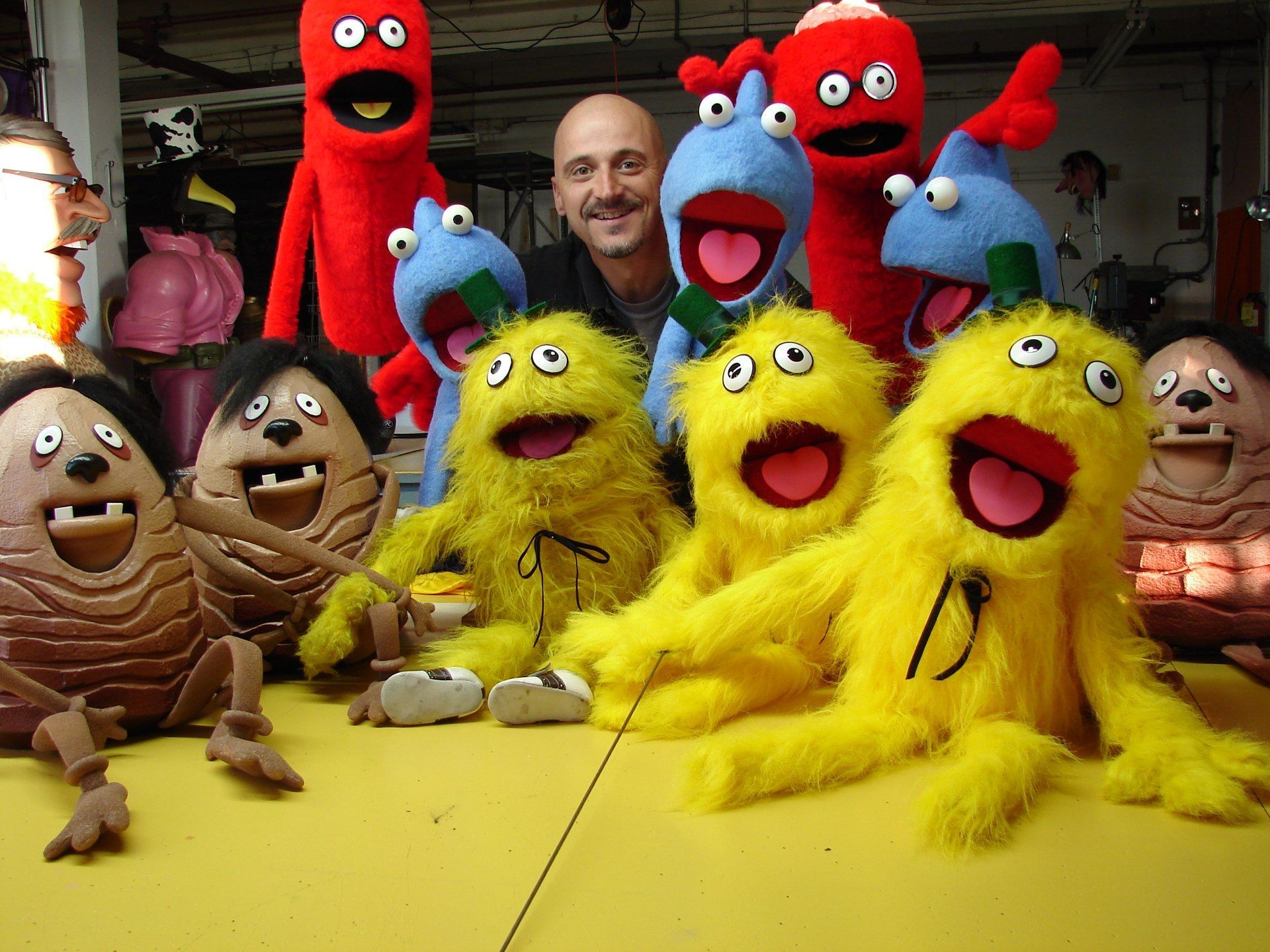 A man is surrounded by yellow and red stuffed animals