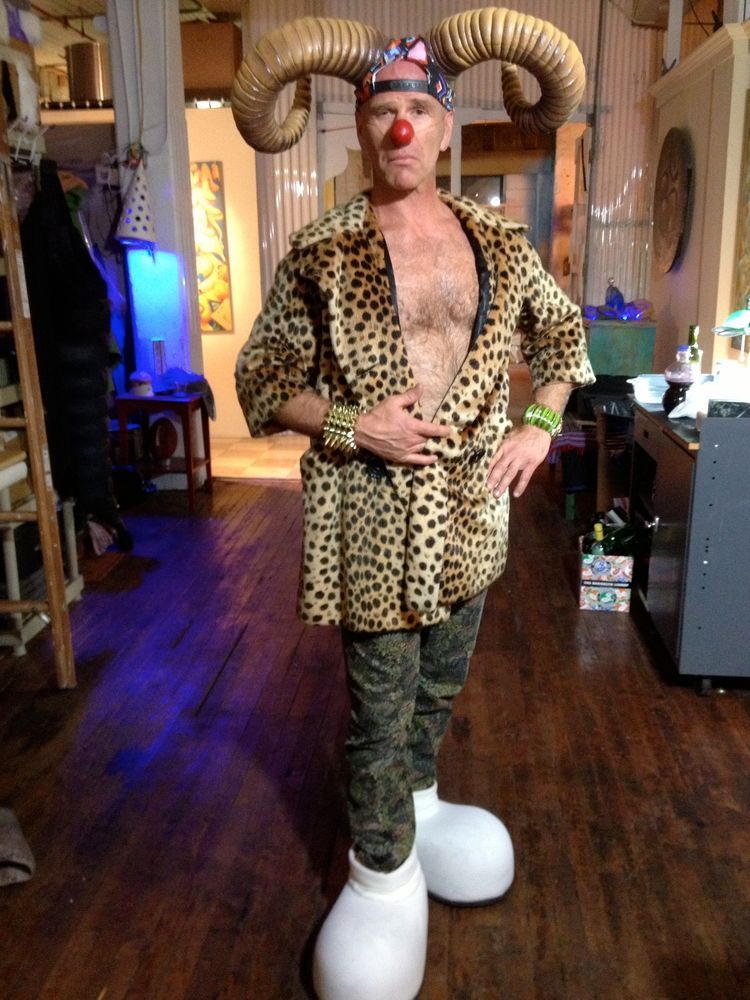 A man is wearing a leopard print coat and a red nose