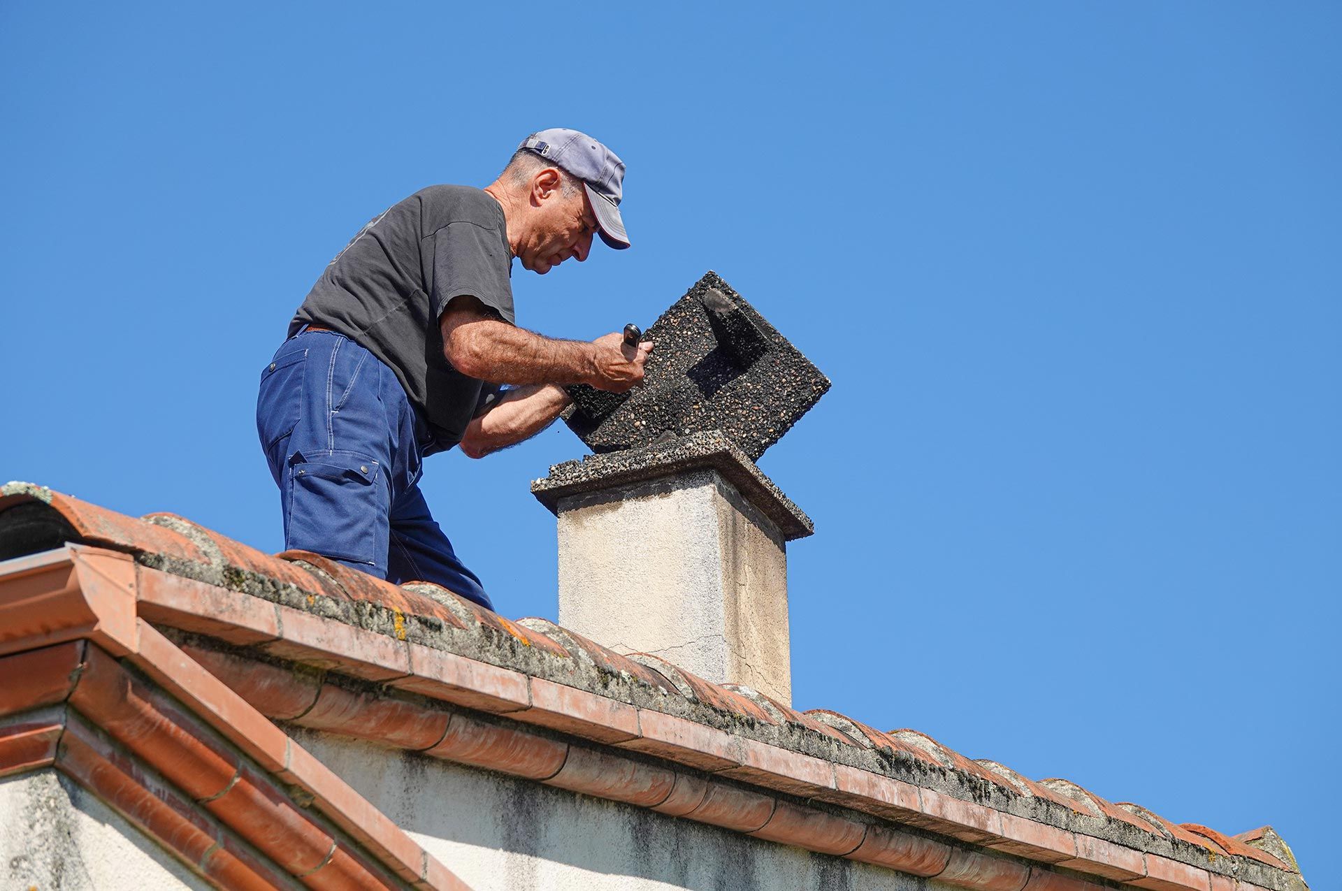 Worker repairs chimney on a roof.
