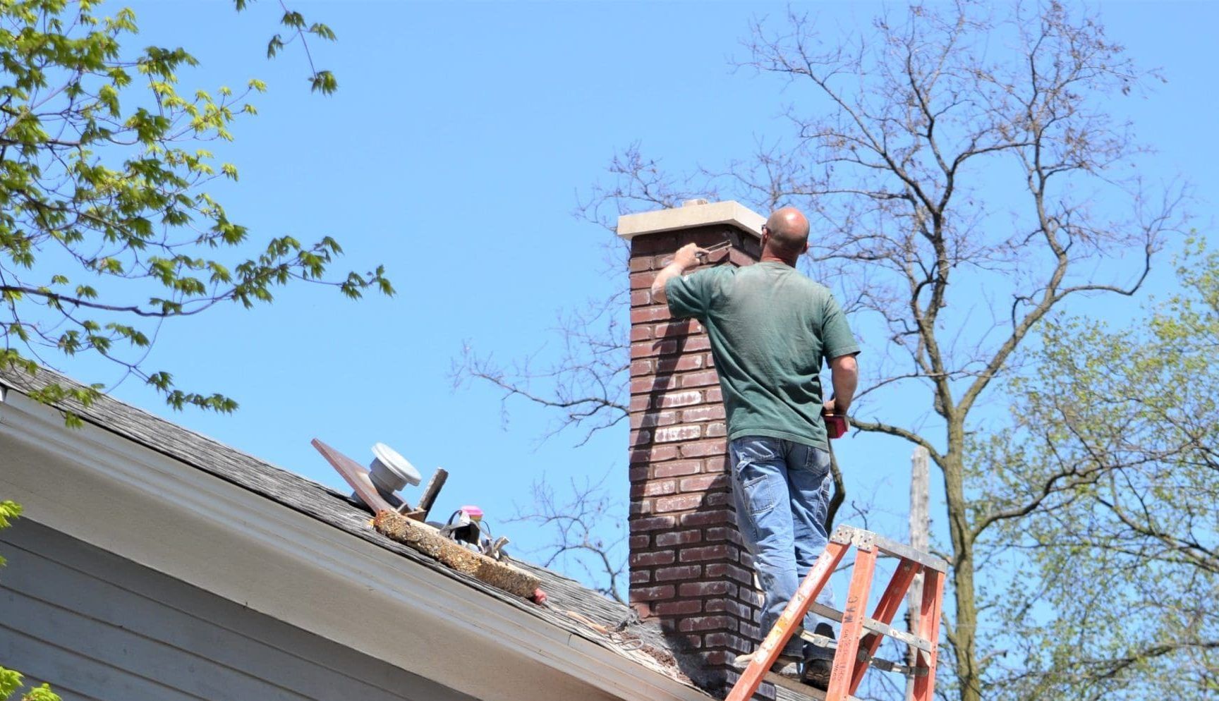 A person performing a chimney maintenance on the rooftop. A person performing a chimney maintenance on the rooftop.