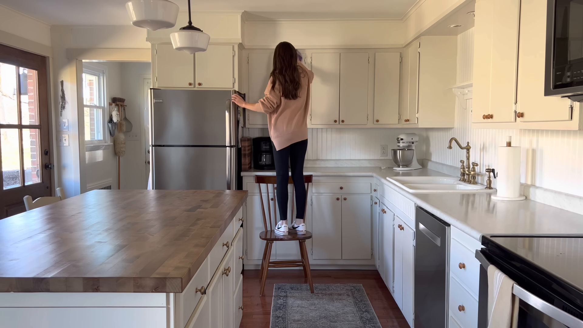 Green Hands cleaner tidying and organizing a bright New York City living room