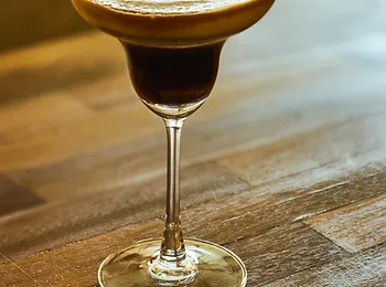 a martini glass filled with a drink on a wooden table .
