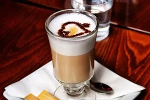 a glass of cappuccino with a heart drawn on it