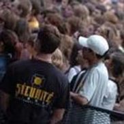 Agent de sécurité en chemise noire avec l'inscription « Sécurité », foule en arrière-plan.