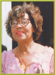 Portrait of a smiling woman in glasses wearing a pink floral blouse against a dark background