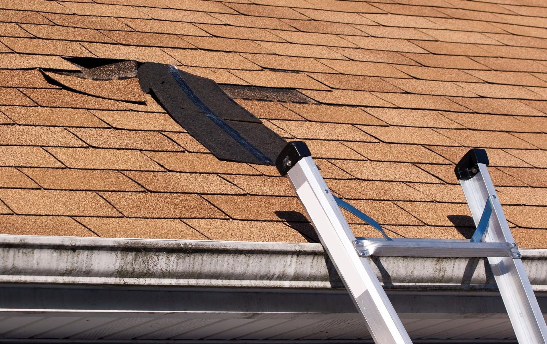 A ladder is sitting on top of a roof with a hole in it.