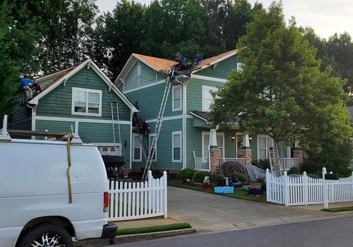 A white van is parked in front of a green house.