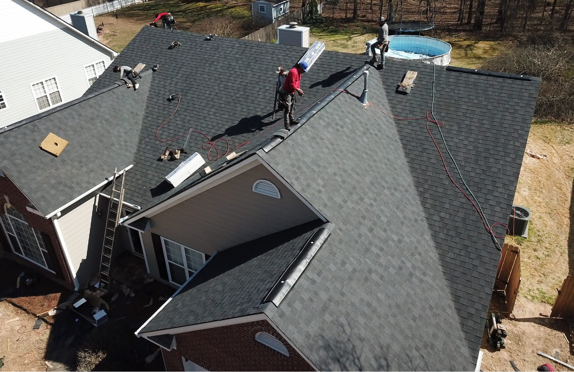 A group of people are working on the roof of a house.