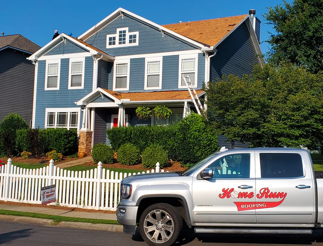 A silver truck is parked in front of a blue house.