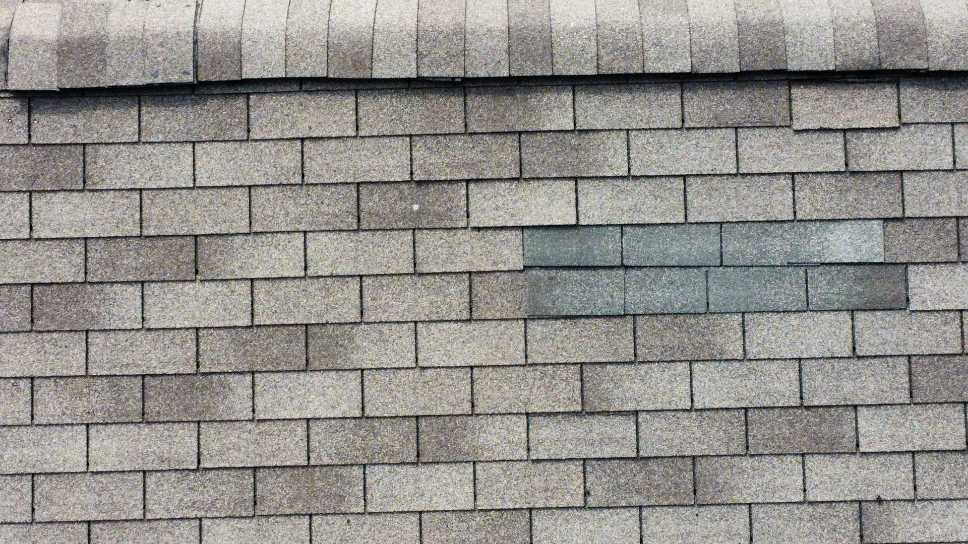 A close up of a roof with a few shingles missing.