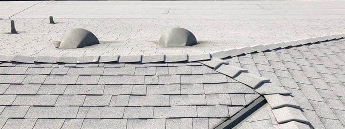 A close up of a roof with a broken shingle.