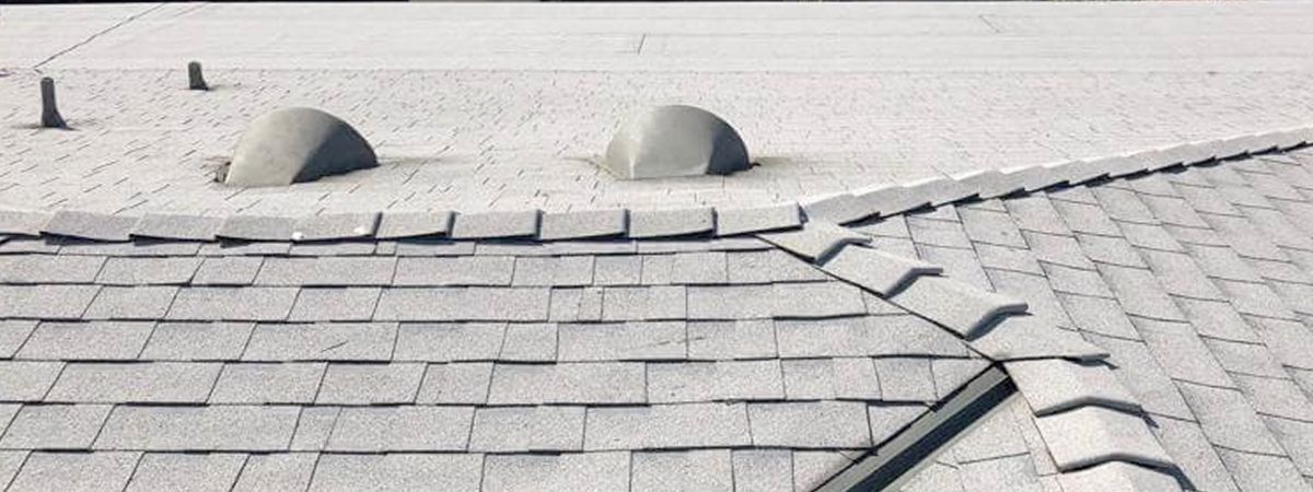 A close up of a roof with a broken shingle.