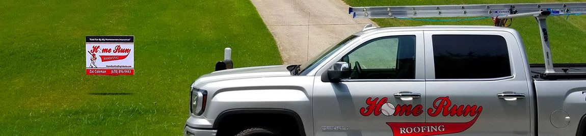 A silver truck is parked in front of a grassy field.