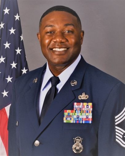 A man in a military uniform is smiling in front of an american flag