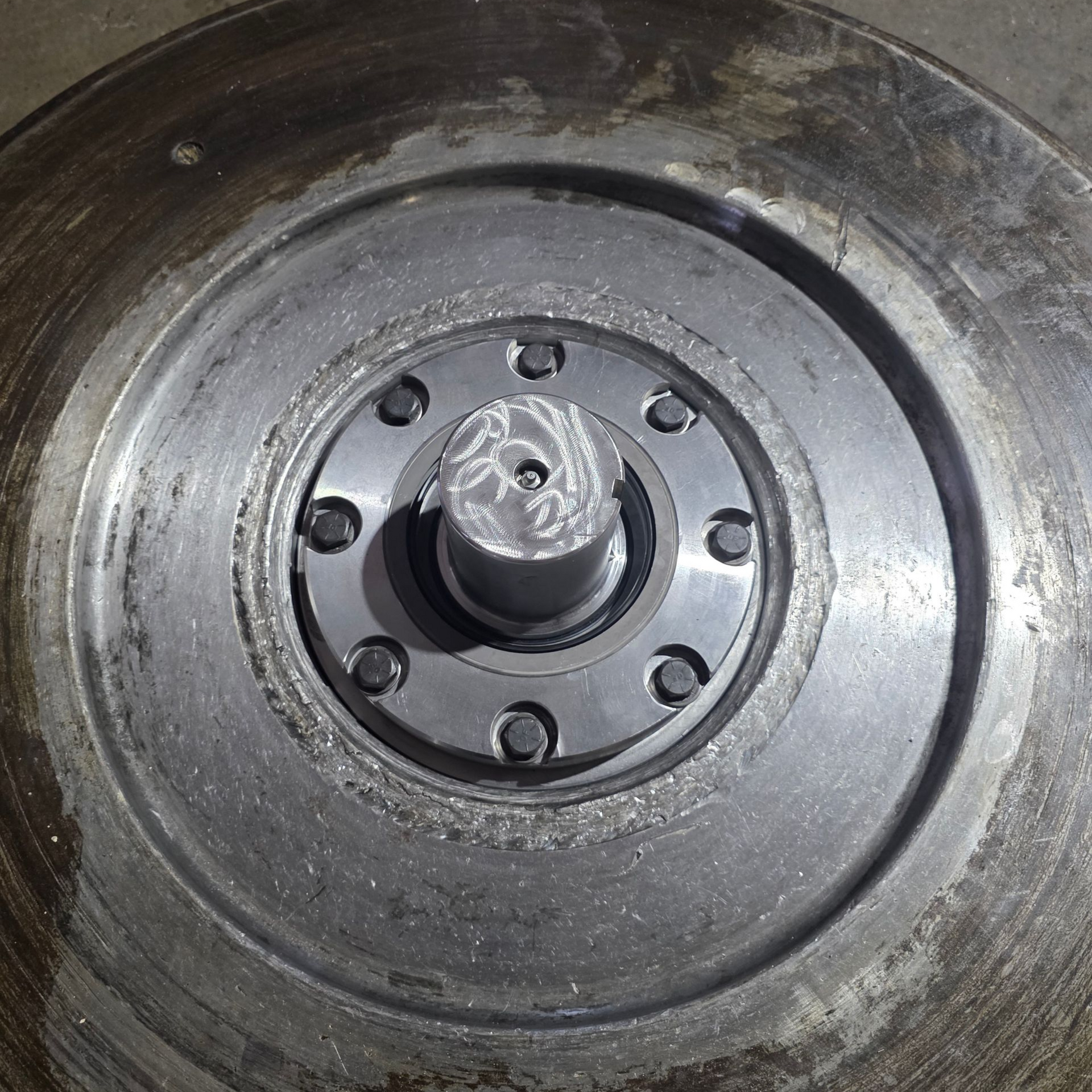 A metal machine component with a central spindle and surrounding circular plates, bolted together.