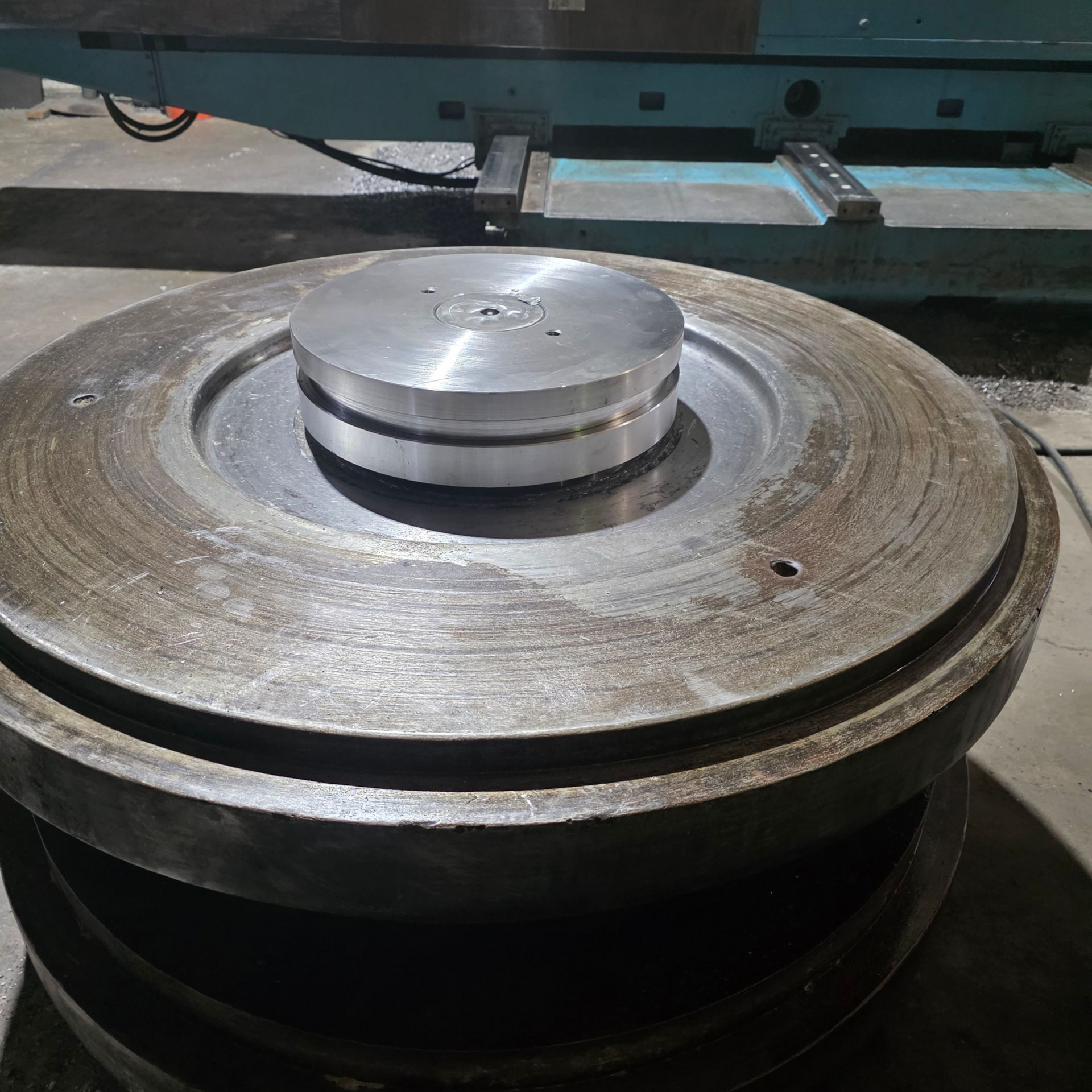 Metal disc stacked on another with a smaller silver disc on top, set against a machine background.