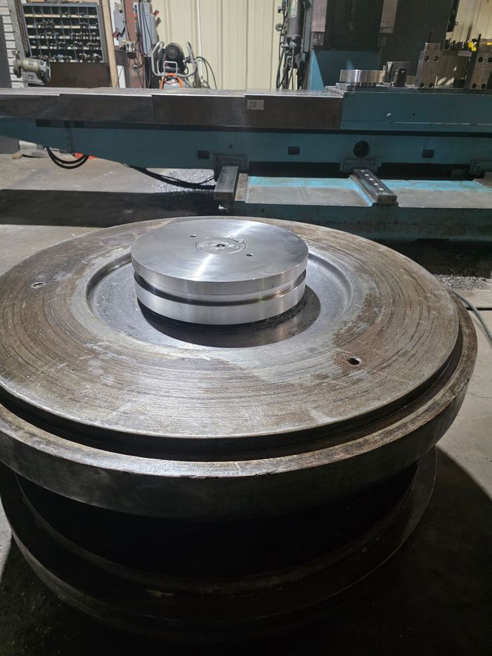 Large metal disc with a smaller silver disc stacked on top, in a machine shop setting.