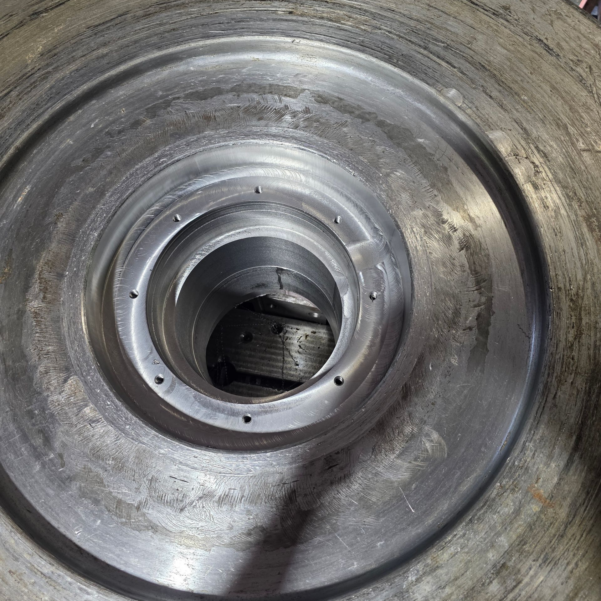 Concentric metal cylinders with a central hole and various smaller holes.