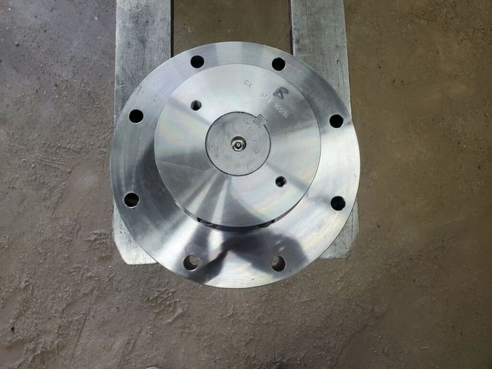 Two circular metal flanges with multiple bolt holes, resting on a metal surface.