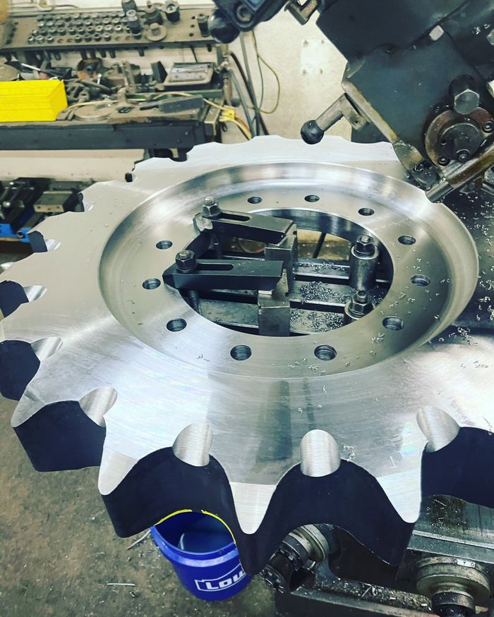 Large gear being machined on a milling machine in a workshop setting.