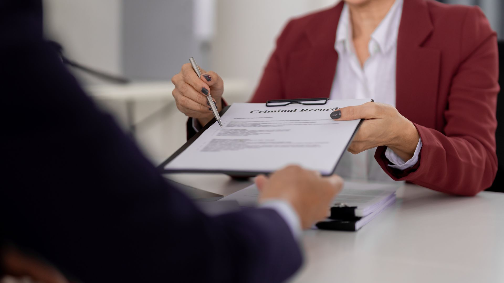 A lawyer reviewing a criminal record document during a legal consultation. A lawyer reviewing a criminal record document during a legal consultation.