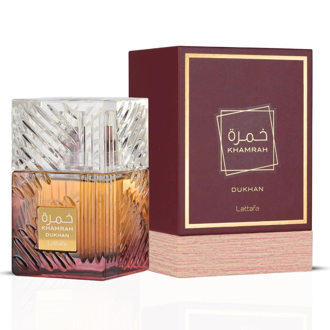 Frasco de perfume con vidrio ámbar facetado junto a una caja de embalaje granate y dorada.