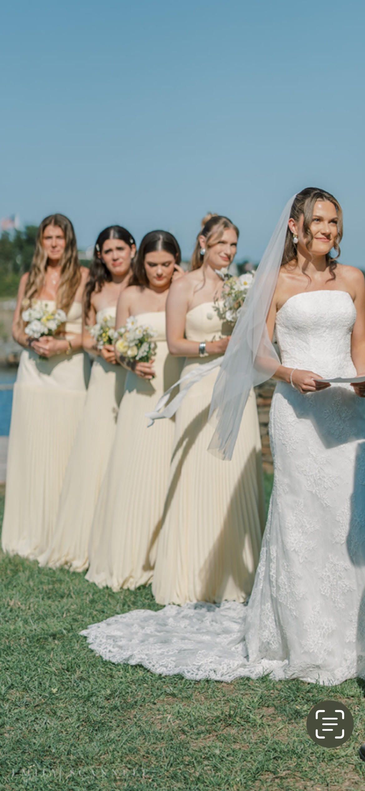 Person standing in a sage green floor-length dress with hands on hips in a bedroom