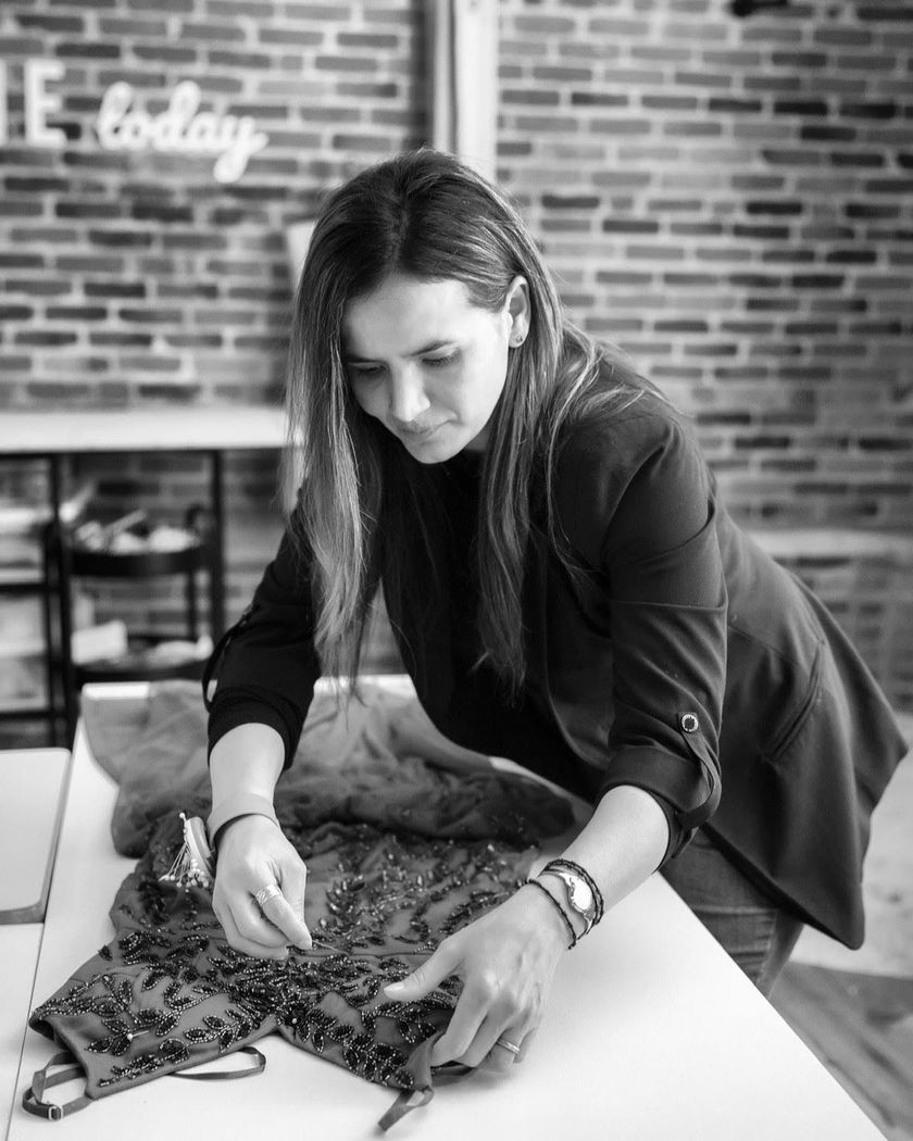 Person arranging a patterned garment on a table in a brick-walled studio