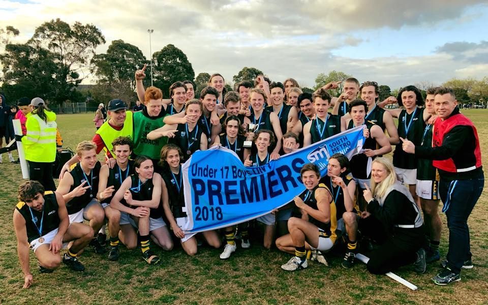 A sports team celebrating on a field, holding a blue banner that reads 