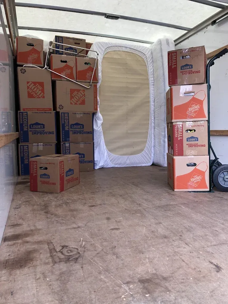 Interior of a moving truck filled with boxes and a mattress.