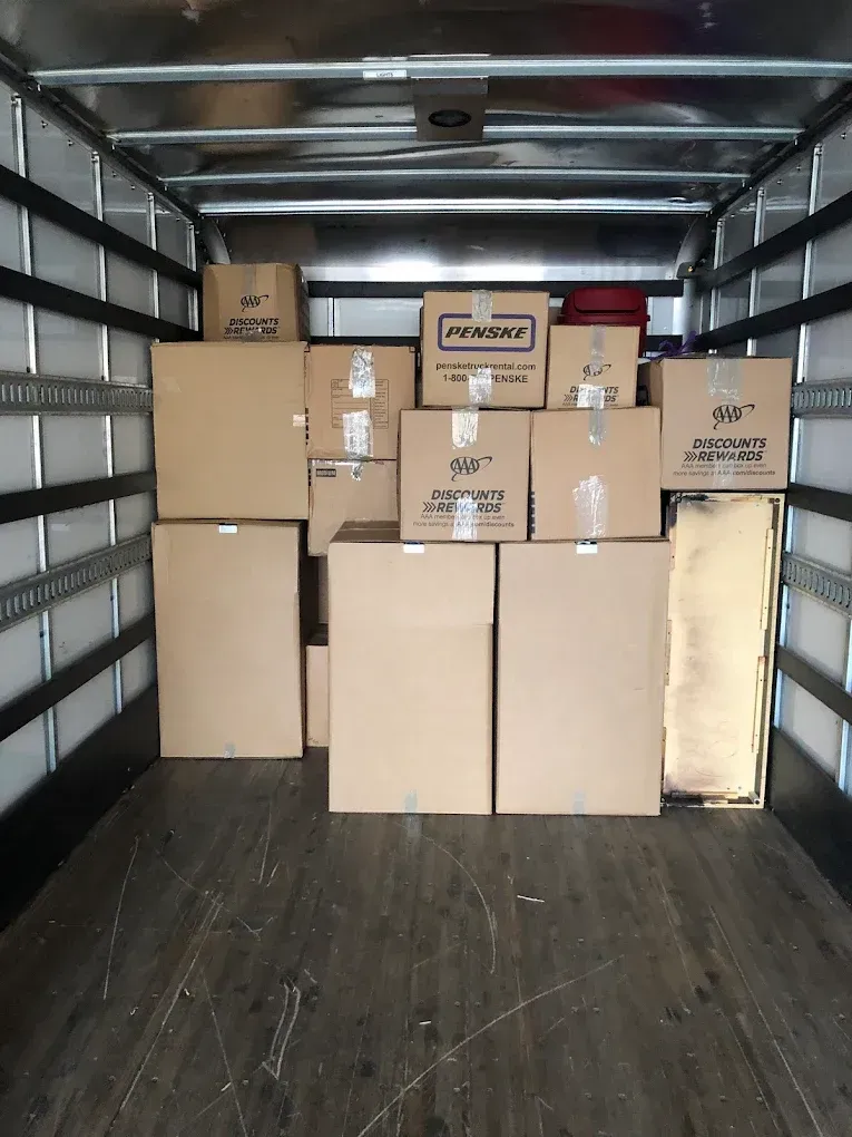 Interior of a moving truck filled with stacked cardboard boxes, ready for transport.