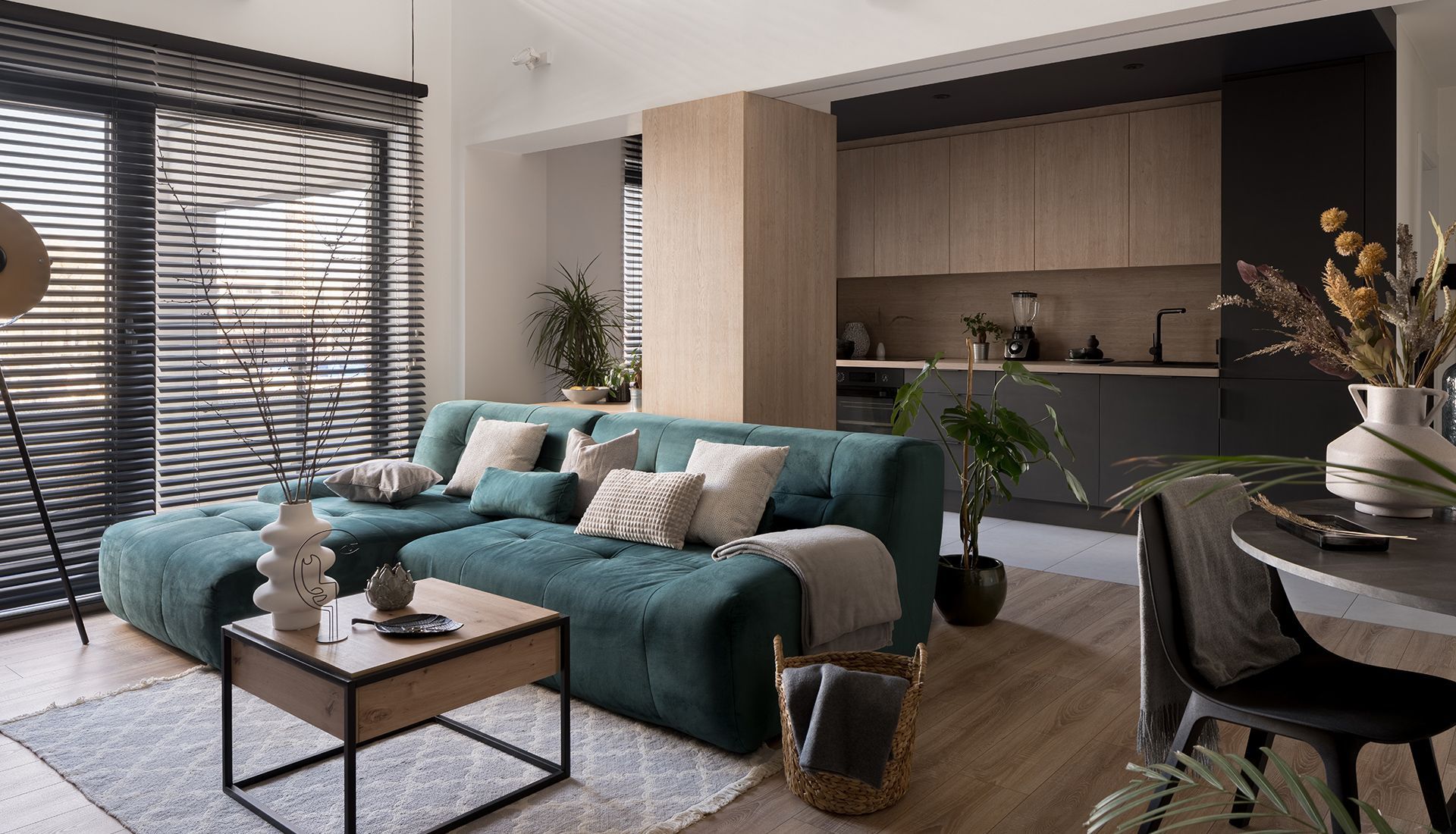 Modern living room with teal sofa, open to a kitchen.