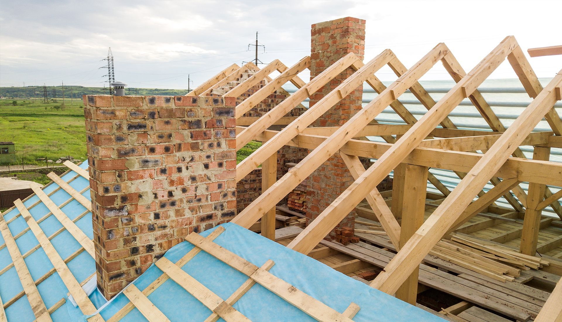 Wooden roof framing with brick chimneys under construction.